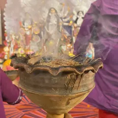 A close up of the dhunuchi, an earthen incense burner filled with coconut husk and camphor. The smoke is an offering to the Goddess Durga during the evening aarti.