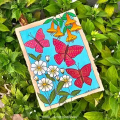 A painting of red butterflies and flowers on handmade paper, nestled amongst real green leaves. This piece was a handmade birthday gift for a dear friend.