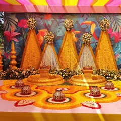 This image focuses on the floor decor for the Haldi ceremony, with floral rangoli patterns made from marigold petals and traditional pots for the rituals.