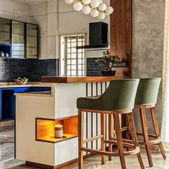 We designed this kitchen with a breakfast counter that doubles as a space divider. The combination of dark blue cabinets, a white and wood counter, and olive green bar stools creates a stylish, contemporary look.