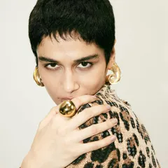 A close-up beauty shot from the Disobedience campaign. The bold gold jewelry and direct gaze of the model add to the fierce, high-fashion mood.