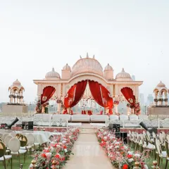 A mandap fit for royalty. This outdoor setup combines traditional Rajasthani architecture with lush floral arrangements, creating a breathtaking aisle for the bride to walk down.