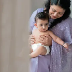 A mother's gentle embrace is a world of comfort for her baby. This soft, naturally lit portrait captures a quiet moment between a mother in a lovely lavender sari and her child.