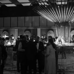 A black and white shot of guests mingling at a stylish cocktail bar, capturing the sophisticated and social atmosphere of the evening.