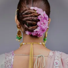 This is the kind of high-end, polished work you'll learn to create. This detailed shot shows a twisted bridal bun, perfectly adorned with a crescent of fresh pink flowers, a style that is both elegant and timeless.