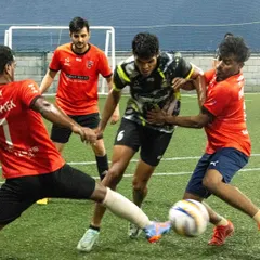 Our player shields the ball under pressure from multiple opponents, showcasing the strength and game intelligence we teach.