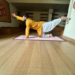 A variation of Balancing Table Pose, using the wall for support. This modification helps students build stability and focus on lengthening the spine before attempting the full, unsupported pose.