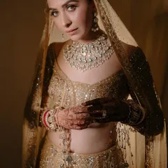 A classic bridal portrait of the beautiful Malvika Raaj. The soft lighting and her direct gaze create a powerful yet graceful image, highlighting the intricate details of her golden lehenga and stunning diamond jewelry.