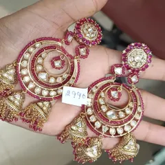 A matching pair to our green chandbalis, these earrings feature rich ruby-colored stones and beads. The intricate kundan work and dangling jhumkas make them a festive favorite.