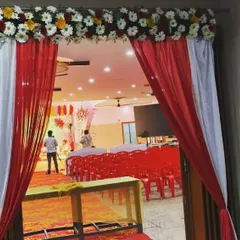 A simple yet effective entrance decoration for a hall, using red and white drapes and a floral border.