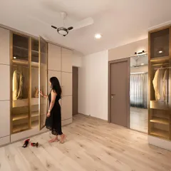 This spacious master bedroom features floor-to-ceiling wardrobes with a mix of solid and tinted glass profile shutters. The internal lighting in the glass sections creates a beautiful display for clothing and adds a touch of luxury to the room.