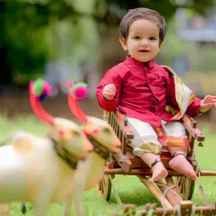 Dressed in a vibrant red silk kurta, little Charul looks like royalty on the mini bullock cart. These traditional outfits add so much richness and meaning to a child's portrait session.