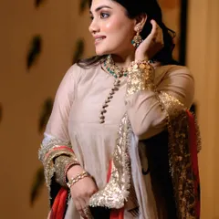A profile shot of the model, her hand gently touching her hair, drawing attention to the elegant earrings and necklace from the designer collaboration.