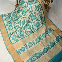 The elegance of the lotus flower is captured in this hand-painted Pen Kalamkari saree. The serene blue lotuses are painted on a natural beige tussar silk base, creating a tranquil and artistic effect.