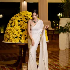 A full-length shot of the white saree against a stunning floral arrangement, showcasing the hotel's beautiful decor.
