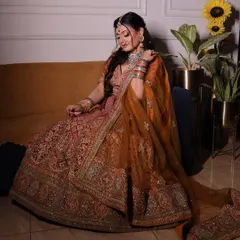 This is the quintessential bridal look. A heavily embroidered lehenga in a rich rust and orange tone, paired with traditional jewelry, captures the timeless elegance every bride dreams of for her wedding day.