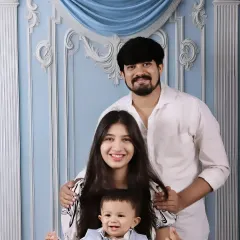 A beautiful family portrait with both parents smiling warmly as they hold their happy baby boy.