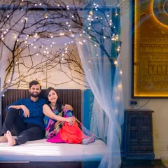 This cozy indoor bed set, decorated with fairy-lit branches, offers a dreamy and intimate setting for couple or maternity portraits, perfect for capturing tender moments.