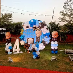 An outdoor Boss Baby themed party on a lawn, with a full backdrop, character cutouts, and a light-up number '4'.