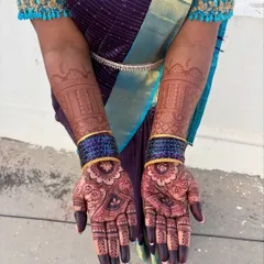 A stunning, dark mehendi stain beautifully complemented by a traditional purple and blue silk saree and matching bangles.