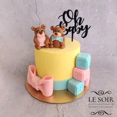 This "Oh Baby" teddy bear cake was for a baby shower. The 1 kg Vanilla Caramel cake is decorated with adorable, hand-sculpted fondant teddy bears, baby blocks, and a large pink bow.