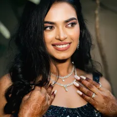 A stunning close-up of the bride, showcasing her flawless makeup and intricate diamond necklace. Her happy, confident smile makes this a radiant and beautiful portrait.