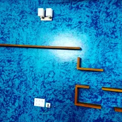 This vibrant blue wall demonstrates a crinkle texture effect, a popular choice for adding character and hiding minor wall imperfections. It serves as a dynamic background for the minimalist wooden shelves in this living space.