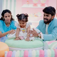 A sweet family moment at a Candyland party. The parents help their daughter, who is sitting on a giant macaron prop, celebrate her special day.