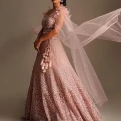 A modern and chic bridesmaid look. This light pink net lehenga with feather-detailed shoulders and a flowing dupatta is perfect for a stylish wedding party.