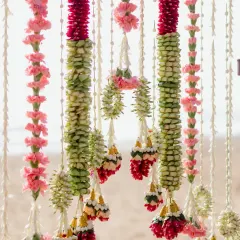 Intricate floral garlands made from carnations and jasmine buds, created for a surreal sunrise wedding by the sea. The craftsmanship in these traditional decorations is simply breathtaking.