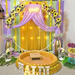 This complete Haldi setup features a sunflower arch, a 'Haldi' neon sign, and a traditional seating area. We've included fun props and decorative birdcages to add a playful touch to the ceremony.