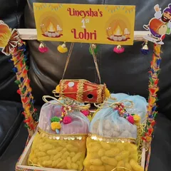 A personalized "First Lohri" hamper in a decorated wooden tray. This one features a mini dhol and potlis filled with peanuts, celebrating a special milestone.