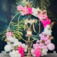A vibrant "Bride to be" decoration against a tropical leaf wallpaper. The circular gold frame is adorned with a bright pink and white balloon garland, creating a fun and trendy look.