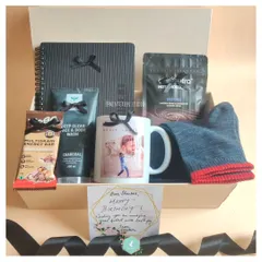 A custom birthday hamper designed around his interests. This gift includes a personalized mug with a photo, a charcoal face and body wash, a multigrain energy bar, a notebook, and cozy socks, making it a thoughtful and practical present.