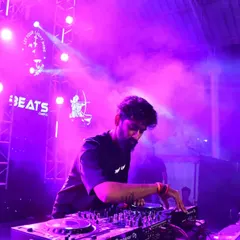 In the zone, mixing tracks on my Pioneer deck under the vibrant purple lights of a packed club. This is where I craft the perfect set, blending beats to keep the dance floor on fire all night.