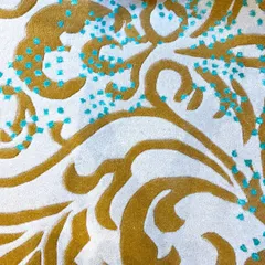 This detail shot highlights the unique texture of our Loops by Zeba collection. Golden swirls are accented with tiny, raised dots of teal, adding a playful and sophisticated touch to the plush ivory background.