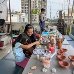 Pottery is a perfect family activity. Here, a mother and daughter are spending quality time together, painting their handmade creations at my open-air studio in Malad.