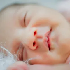 There is nothing more perfect than a newborn's sleepy smile. This macro shot focuses on the tiny, delicate features of a sleeping baby, from their little nose to their perfectly shaped lips, preserving the details you'll want to remember forever.