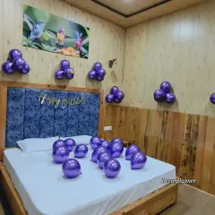 Another angle of the simple purple balloon decoration, showing how it can brighten up a room with wood-paneled walls. The metallic shine of the balloons adds a touch of elegance.