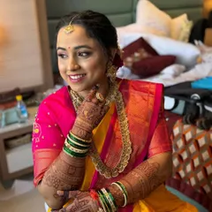 This candid shot captures the bride's happy smile. The makeup is subtle, with a natural glow that perfectly complements her traditional Maharashtrian jewelry and attire.