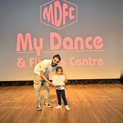 That proud smile says it all. After every performance, I make sure to celebrate each student's hard work with a certificate of achievement. This moment with one of my youngest dancers captures the personal encouragement I provide to every child.