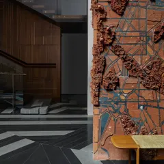 A terracotta wall mural by artist Pravat M provides a deeply textural and narrative element. The raw, earthy quality of the clay contrasts with the polished, geometric pattern of the black and white granite floor.