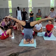 Demonstrating a variation of Sirsasana (Headstand) to students at a workshop. The group setting allows for shared learning and observation.