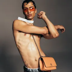 A dynamic shot for a Calvin Klein campaign, highlighting the brand's modern aesthetic. The composition uses strong lines and a confident pose to create an edgy, commercial photograph.