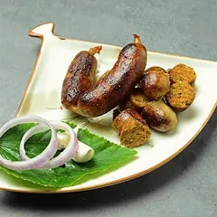 Our handmade Thai Sai Oua pork sausages, beautifully plated and ready to eat. These are packed with the fresh flavors of Thai galangal, lemongrass, and kaffir lime, offering a zesty and aromatic experience.