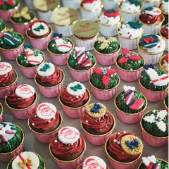 A large order of my handcrafted Christmas cupcakes. This assortment includes various festive designs like Santa Claus faces, wreaths, stockings, and presents, perfect for corporate parties or family gatherings.
