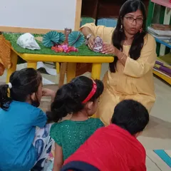 Children gather around the story table to get a closer look at the props used in our anniversary storytelling of "The Three Little Pigs."