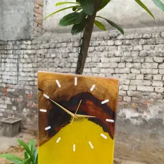 This rectangular clock combines natural wood with a vibrant yellow resin pour. It's a modern and cheerful piece of wall decor, seen here hanging from a tree branch in my studio garden.