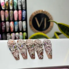 A showcase of our intricate 3D floral nail art. These long, coffin-shaped nails feature sculpted flowers embellished with sparkling rhinestones, demonstrating our advanced design capabilities.