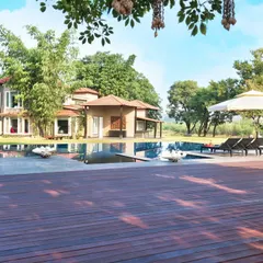 A view of the Aishbagh holiday home from the expansive wooden pool deck. The design prioritizes outdoor living, with spaces like this deck, a gazebo, and an infinity pool creating a seamless connection to the surrounding landscape.